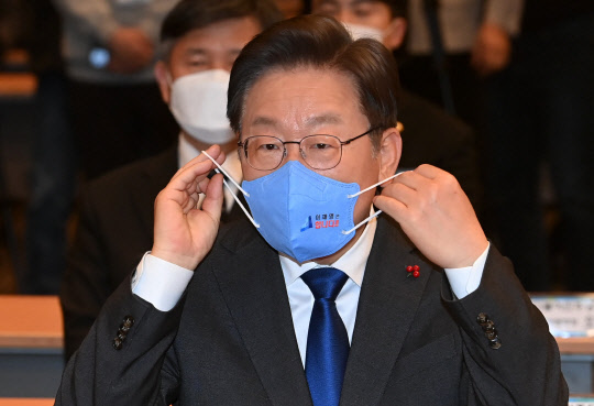 더불어민주당 이재명 대선후보가 23일 서울 여의도 중소기업중앙회에서 열린 대한민국 대전환 직능본부 출범식에서 마스크를 바꿔쓰고 있다.   [국회사진기자단]